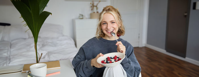 Portrait of smiling young woman holding food at home