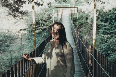 Young woman looking at railing on footbridge