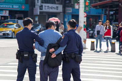 Rear view of people standing on street in city