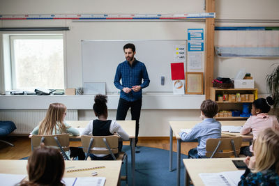 Confident teacher explaining students in classroom at school