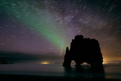 Silhouette built structure on sea against sky at night