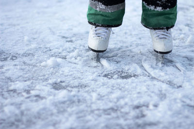 Children feet in white skates stand on the ice. ice skating on a frosty winter day.