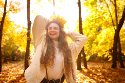 Portrait of young woman standing against trees