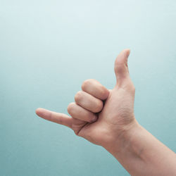 Cropped hand gesturing against turquoise background