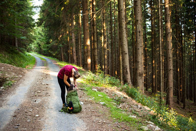 Woman cycling on road amidst trees in forest