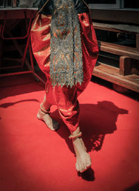 Low section of woman wearing traditional clothing dancing on red floor