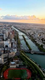 High angle view of river amidst buildings against sky during sunset