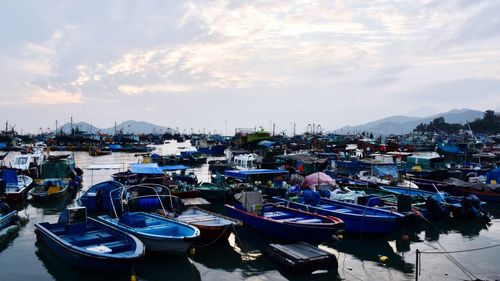 Boats moored at harbor in city against sky