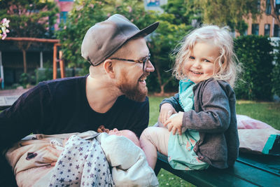 Happy father looking at daughter while holding son in park