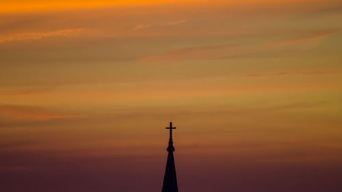 Cross on top of church against sky during sunset