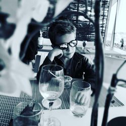 Boy wearing sunglasses sitting by food at table