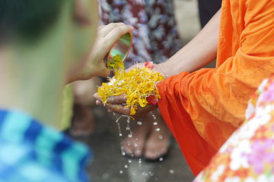 Man pouring water on hands of person carrying flower petals