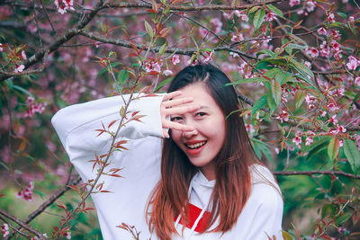 Portrait of smiling young woman with raised arm