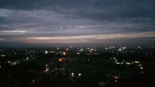 Illuminated cityscape against sky at night