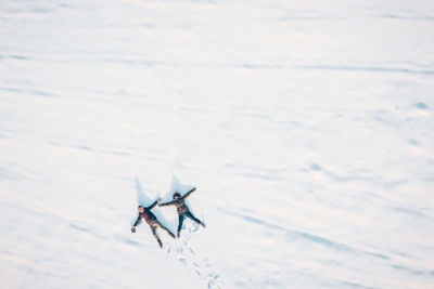 Aerial view of friends lying on snow covered field