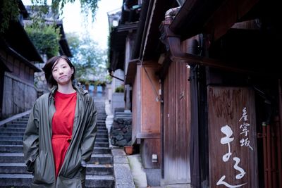 Portrait of woman standing against building