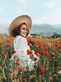 Young woman with pink flowers in field