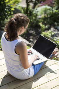 High angle view of mid adult woman using laptop on terrace