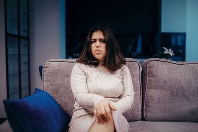 Portrait of young woman sitting on sofa at home