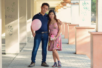 Full length portrait of young couple standing in corridor