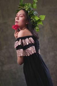 Midsection of woman holding rose while standing by plant