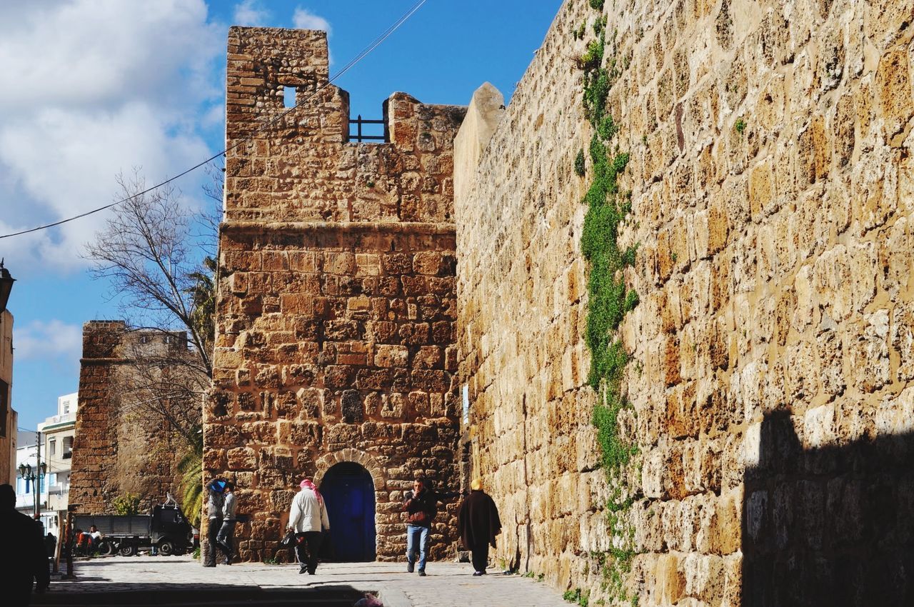 architecture, built structure, building exterior, history, stone wall, old ruin, sky, old, ancient, the past, men, arch, ancient civilization, walking, wall - building feature, person, brick wall, castle