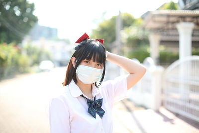 Portrait of young woman wearing mask standing outdoors