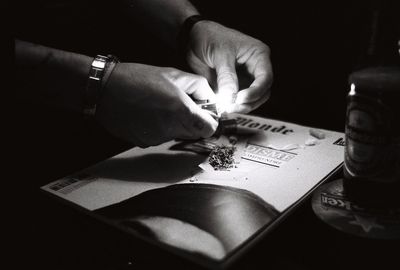 Cropped image of man hands making rolling marijuana over magazine