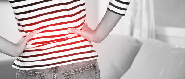 Midsection of woman with arms crossed on bed at home