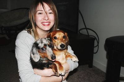 Portrait of smiling woman holdings dogs at home