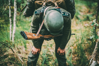 Tired soldier with rifle standing in forest