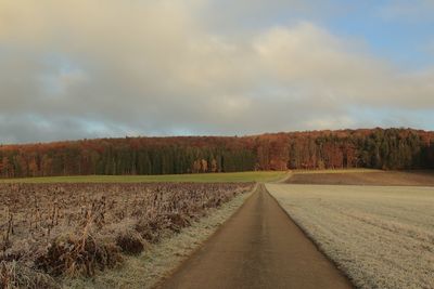 Road amidst field against sky