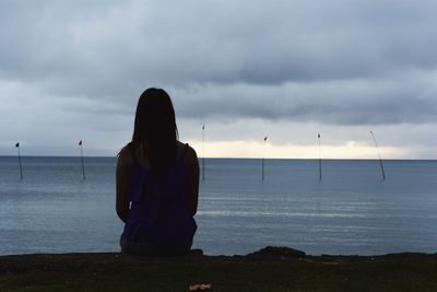 Rear view of woman on beach against sky