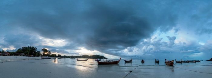 Panoramic view of people on beach against storm clouds