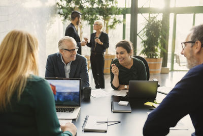 Smiling businesswoman discussing with colleagues in creative office