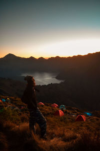 People on land against sky during sunset