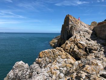 Rock formations by sea against blue sky