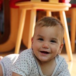 Portrait of cute cheerful baby boy lying on floor at home