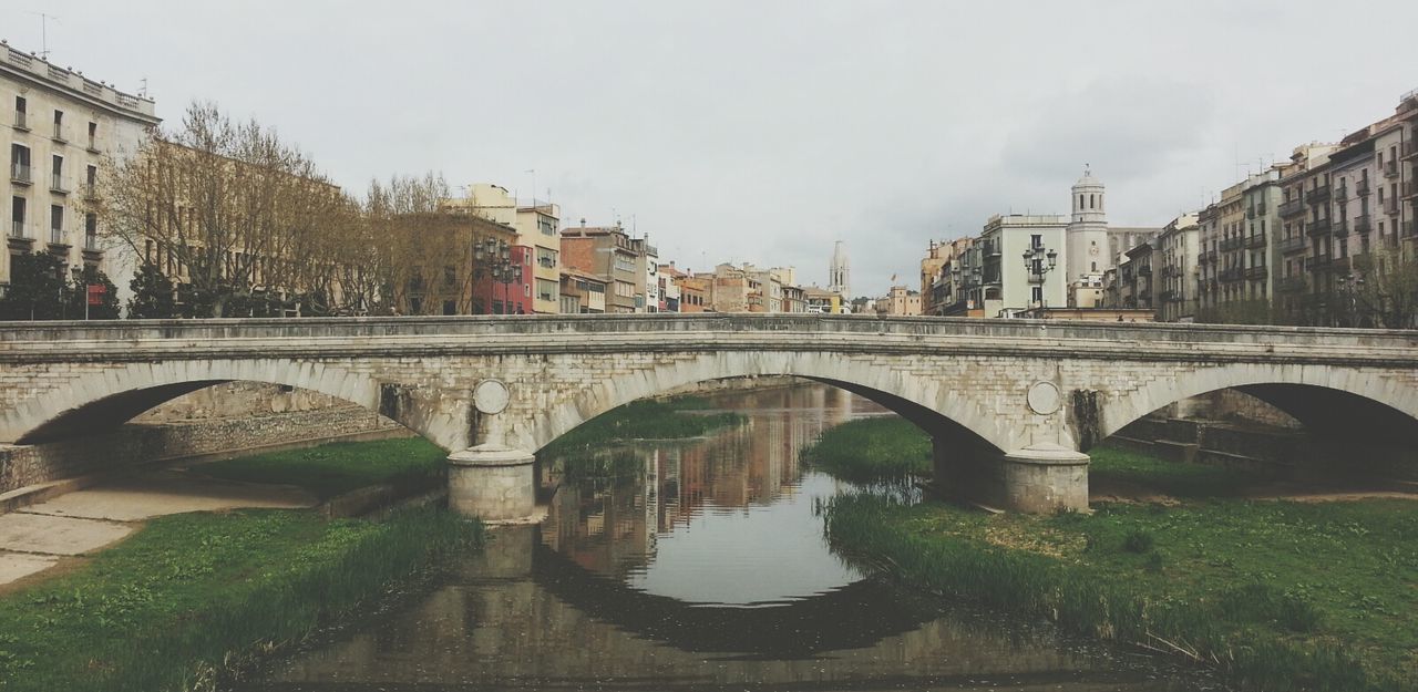 architecture, built structure, bridge - man made structure, connection, building exterior, arch, water, arch bridge, canal, bridge, river, tree, sky, city, reflection, transportation, day, residential building, outdoors, incidental people