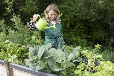 Smiling woman holding fresh green plants