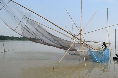 Fishing net in lake against sky