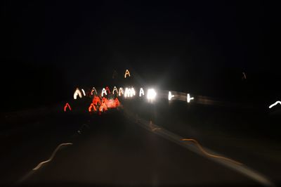 People on illuminated road against sky at night