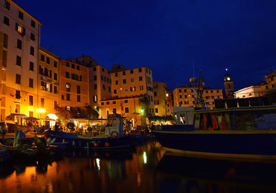 Boats moored in illuminated canal amidst buildings in city at night