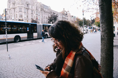 Woman using mobile phone in city
