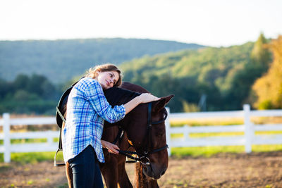 Young woman with horse standing on field