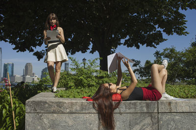 Two young women on the ledge of a garden