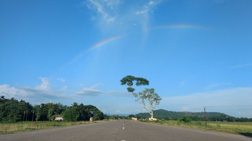 Rainbow over road against blue sky