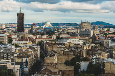 High angle view of city buildings against cloudy sky