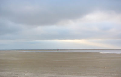 Scenic view of beach against cloudy sky