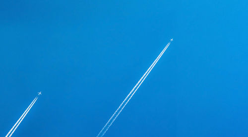 Airplane with white condensation tracks. jet plane on clear blue sky with vapor trail. travel